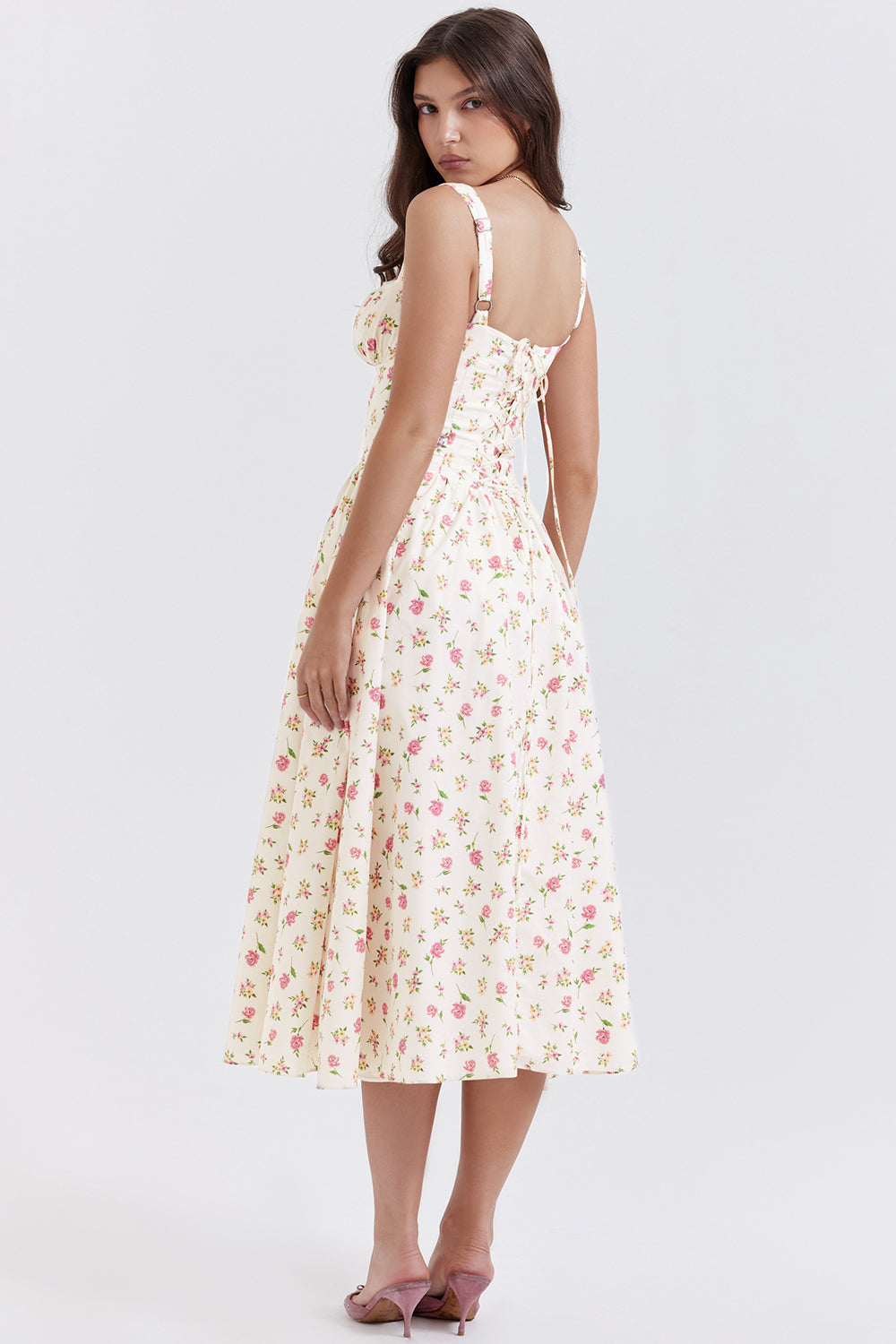 Robe longue à fleurs roses et jaunes, dos nu, portée par une femme aux cheveux bruns. Style estival élégant, mode féminine tendance.