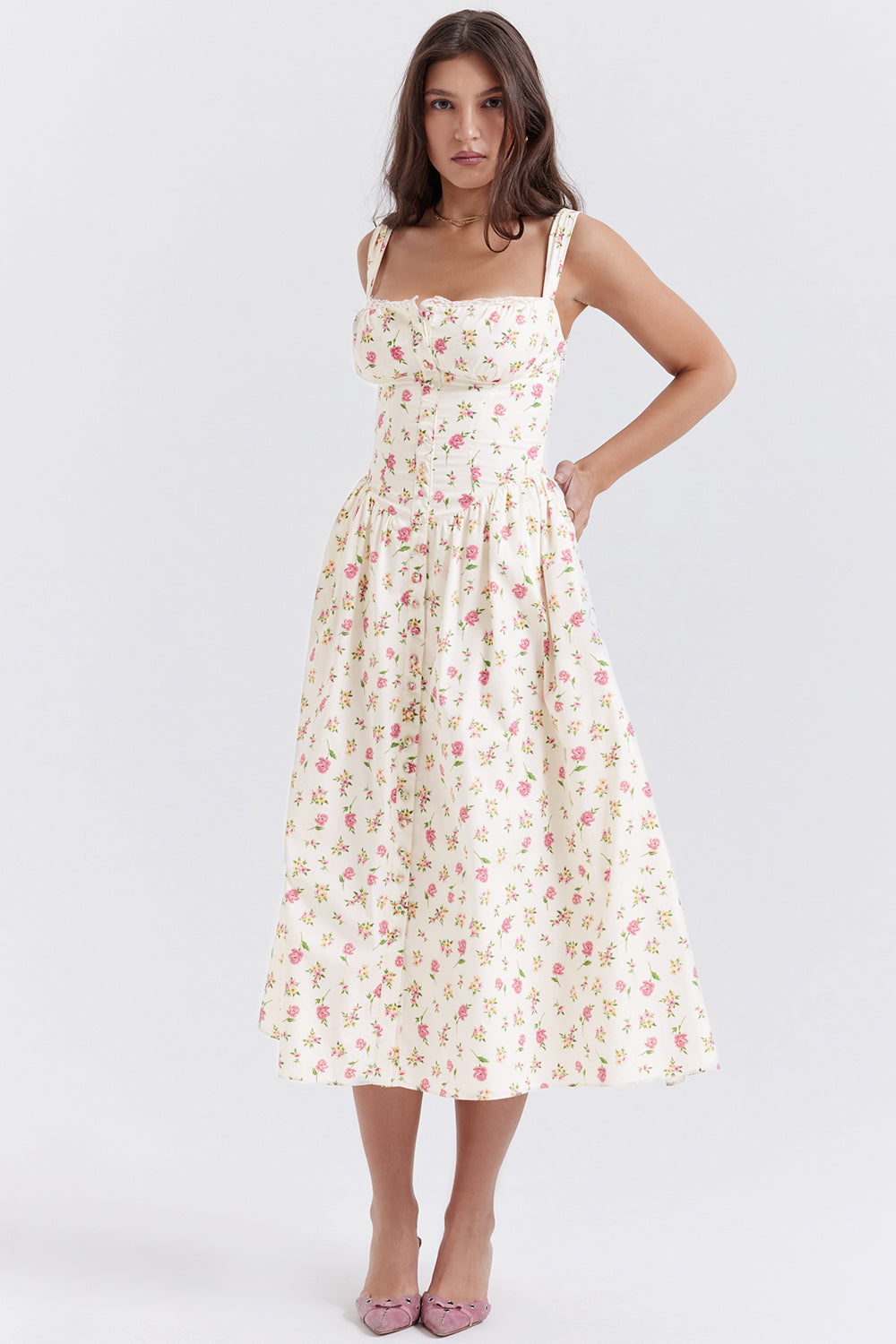 Robe longue à fleurs blanches et roses portée par une femme, style vintage, bretelles larges, idéale pour l'été et les occasions spéciales.