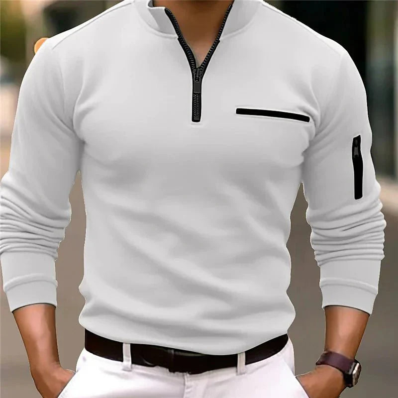 Homme portant un pull blanc à col zippé, poche poitrine et manche, style décontracté. Mode masculine, tenue élégante, tendance automne-hiver.