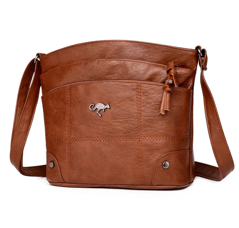 Sac à bandoulière en cuir marron avec logo kangourou, poches avant zippées, design élégant et pratique pour femmes, mode et accessoires tendance.