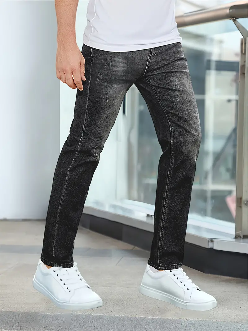 Jeans noirs délavés pour homme, coupe droite, portés avec des baskets blanches. Mode masculine décontractée, tendance urbaine.