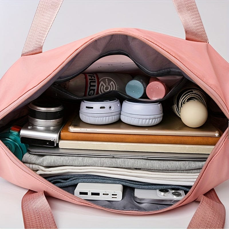 Sac de sport rose ouvert avec vêtements, bouteille d'eau, écouteurs, appareil photo, tablette et chargeur. Accessoires de voyage organisés.