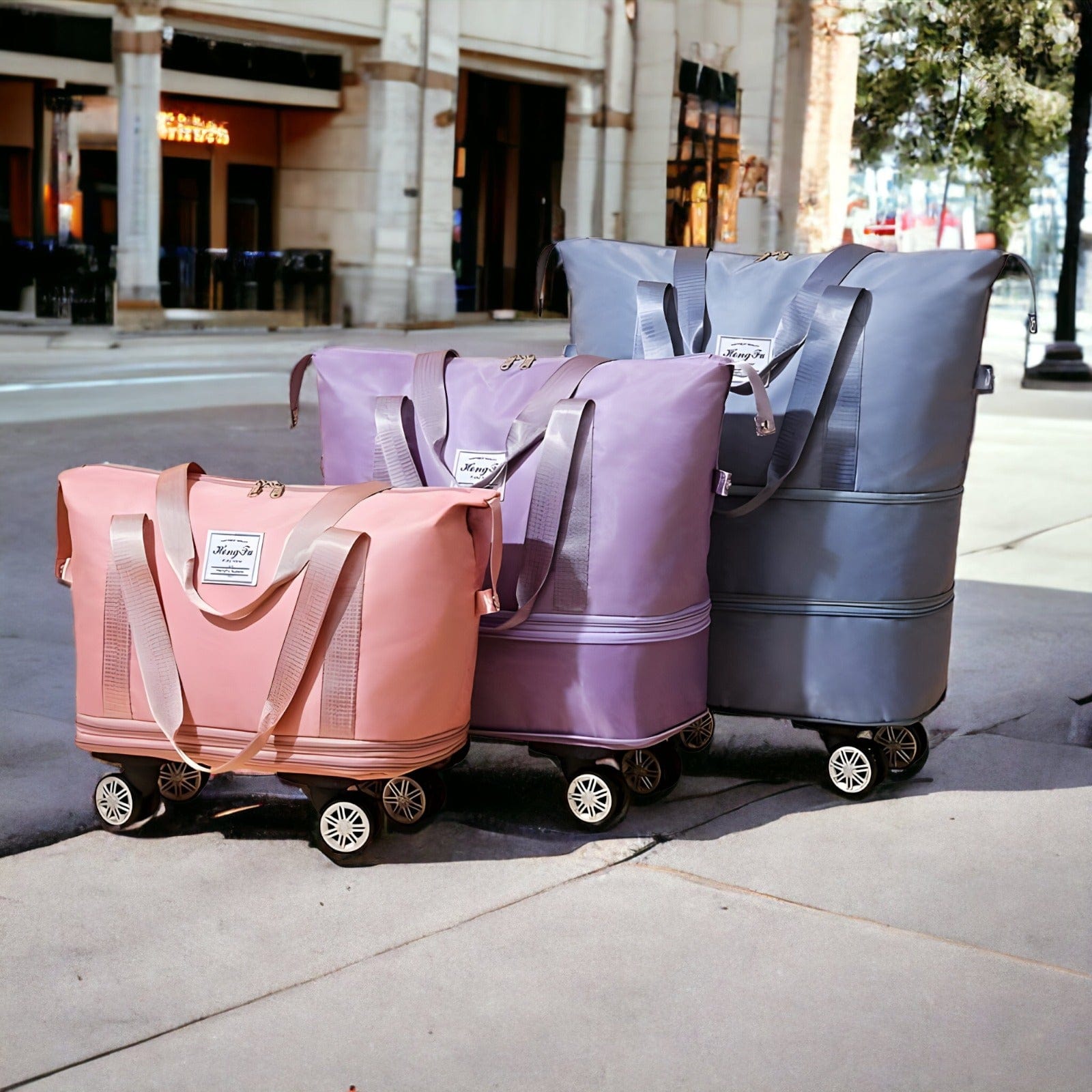 Trois sacs de voyage à roulettes, rose, violet et gris, posés sur un trottoir urbain. Design moderne, spacieux, idéal pour le shopping et les voyages.