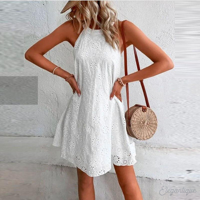 Robe d'été blanche en dentelle portée par une femme avec sac rond en osier, chapeau de paille, style bohème chic, mode féminine estivale.