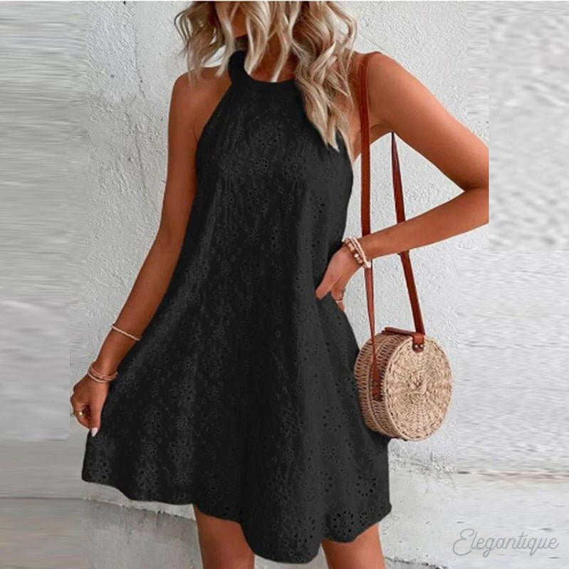 Robe noire en dentelle sans manches, femme blonde, sac rond en osier, mode estivale élégante, tenue décontractée chic, style tendance.
