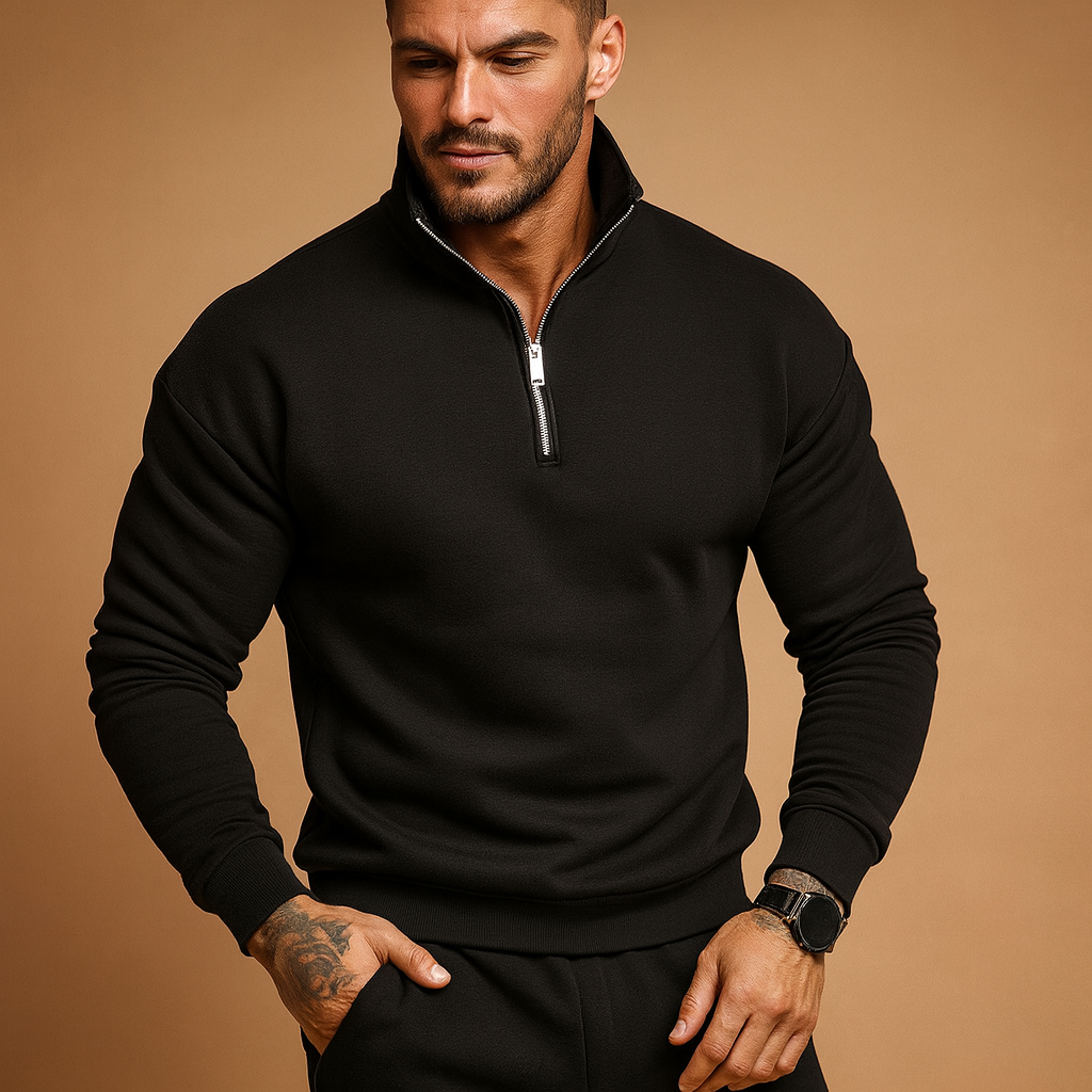 Homme portant un pull noir à col zippé, posant sur fond beige. Mode masculine, style décontracté, montre-bracelet élégante.