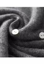 Gros plan sur un pull en cachemire gris avec boutons blancs, texture douce et luxueuse, mode hiver, vêtement chaud et élégant.