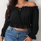 Femme portant un haut noir à épaules dénudées et manches longues, associé à un jean bleu. Mode féminine, style décontracté, tendance actuelle.