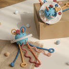 Jouet sensoriel pour bébé en silicone bleu avec anneaux et textures variées, posé sur une boîte en carton. Accessoire d'éveil Montessori.