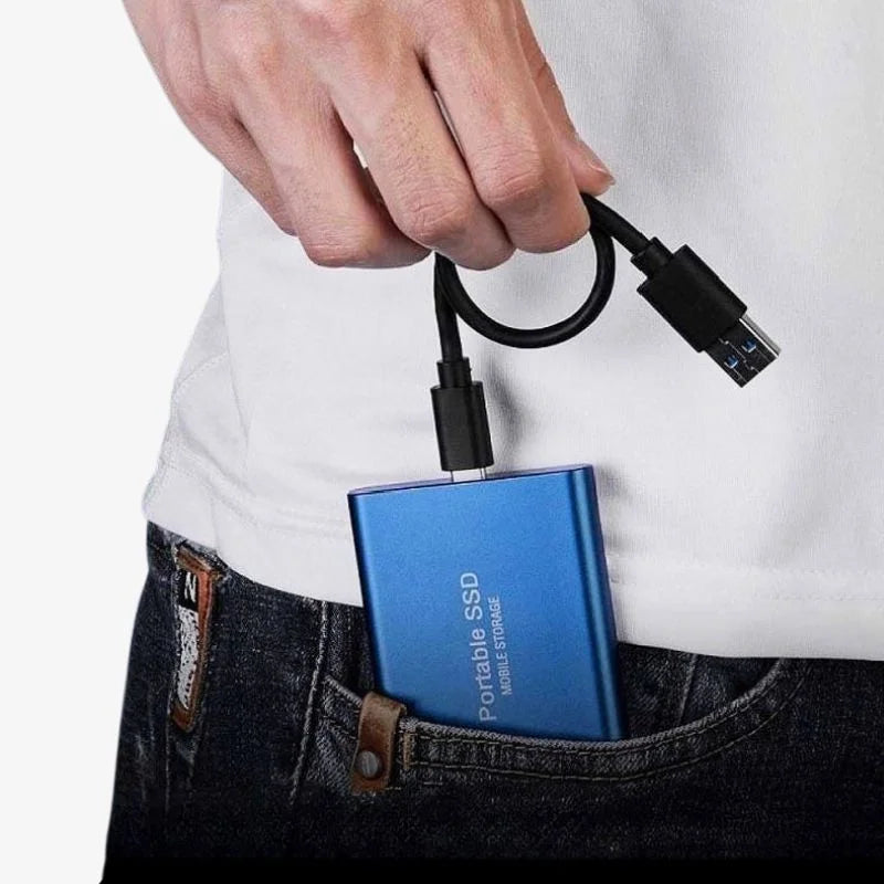 Homme tenant un disque SSD portable bleu avec câble USB, sortant d'une poche de jean. Stockage externe rapide, technologie moderne.