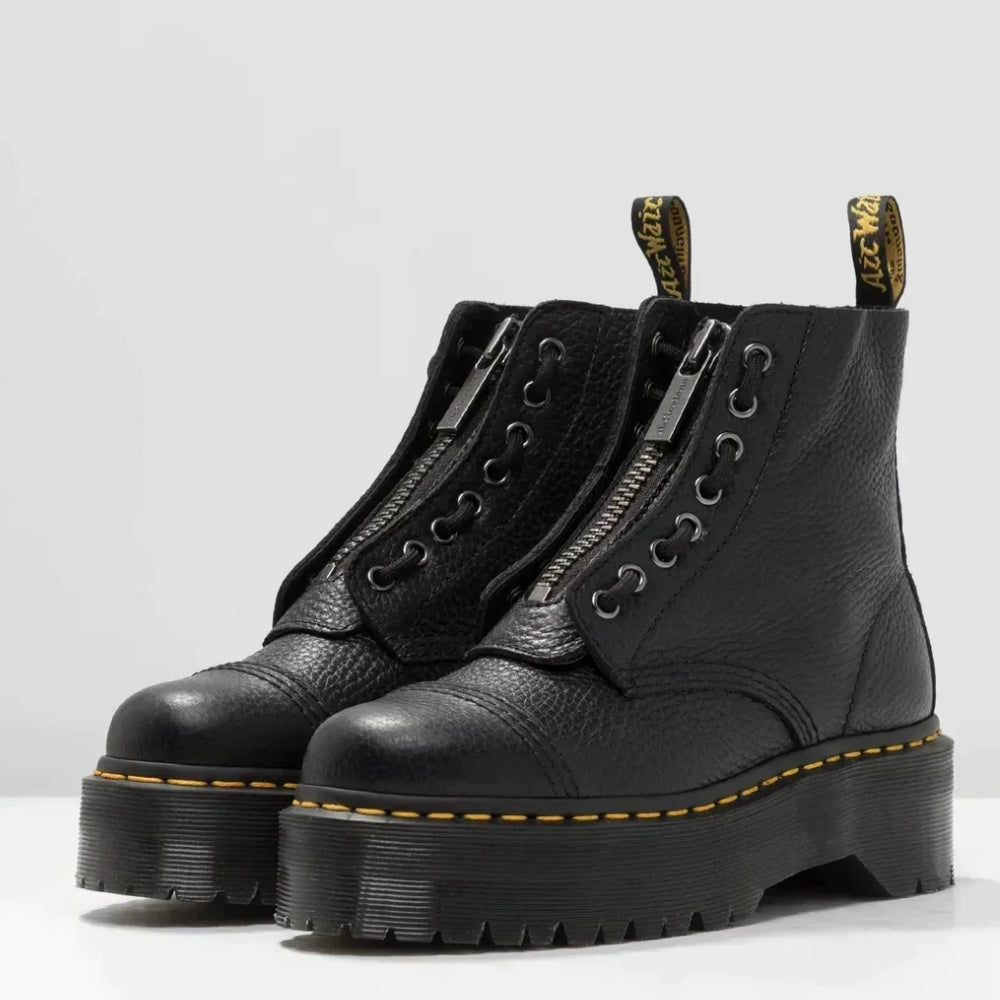 Bottes noires en cuir avec fermeture éclair, semelle épaisse crantée, coutures jaunes, style punk rock. Chaussures tendance, mode automne-hiver.