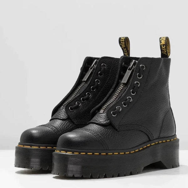 Bottes noires en cuir avec fermeture éclair, semelle épaisse crantée, coutures jaunes, style punk rock. Chaussures tendance, mode automne-hiver.