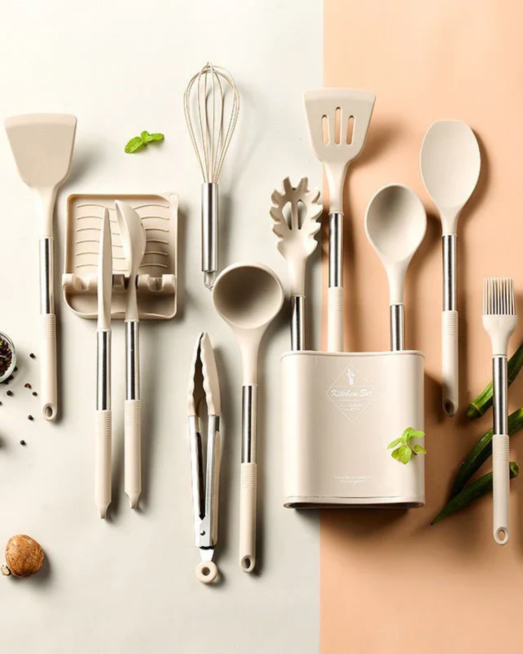 Ustensiles de cuisine en silicone beige avec manches en acier inoxydable, comprenant spatules, fouet, pinceau et couteaux, sur fond bicolore.