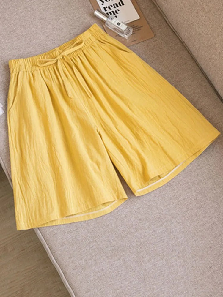 Short jaune en lin sur canapé beige, style décontracté, taille élastique, idéal pour l'été. Mode estivale, vêtements légers, confort quotidien.