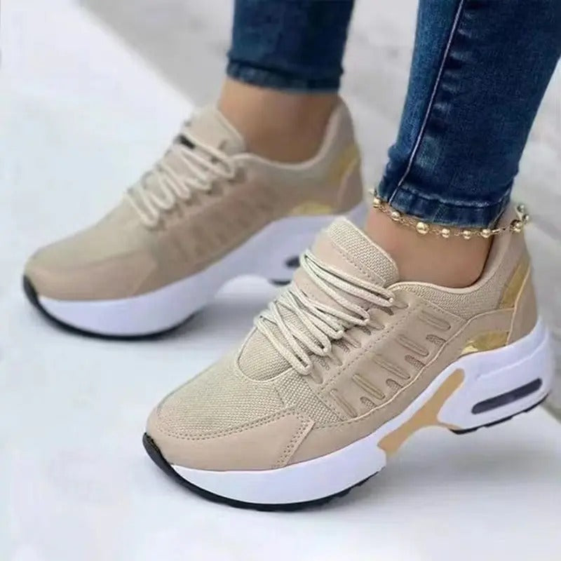 Baskets beiges pour femme avec semelle épaisse blanche, détails dorés, portées avec un jean. Chaussures de sport tendance et confortables.