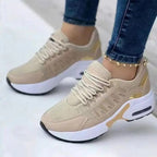 Baskets beiges pour femme avec semelle épaisse blanche, détails dorés, portées avec un jean. Chaussures de sport tendance et confortables.