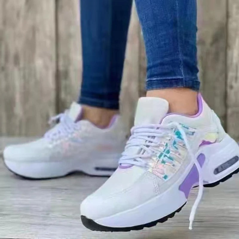 Baskets blanches modernes avec détails violets et semelle épaisse, portées avec un jean. Chaussures tendance pour femme, style décontracté.