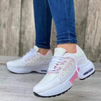 Baskets blanches et roses pour femme, style moderne, portées avec un jean. Chaussures de sport tendance, confortables, idéales pour la marche.
