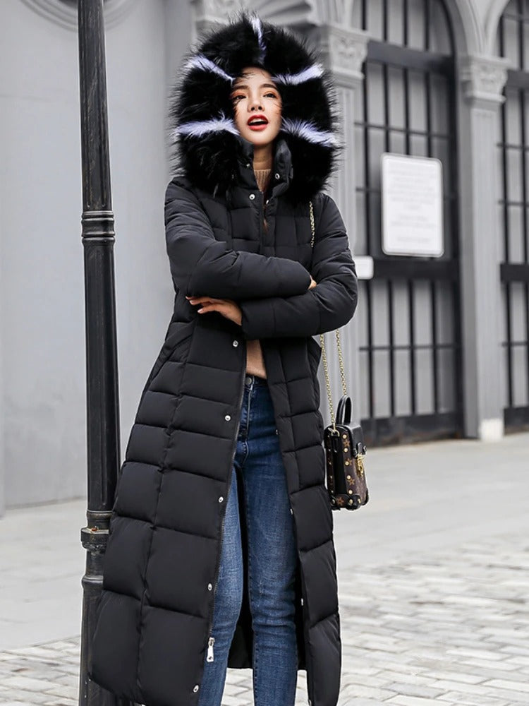 Femme portant un manteau long noir avec capuche en fourrure, debout dans la rue. Mode hiver, tenue élégante, look urbain.