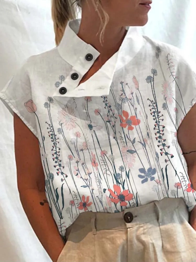 Blouse blanche à col montant avec boutons, ornée de motifs floraux colorés. Mode féminine élégante, tendance printemps-été, style décontracté.