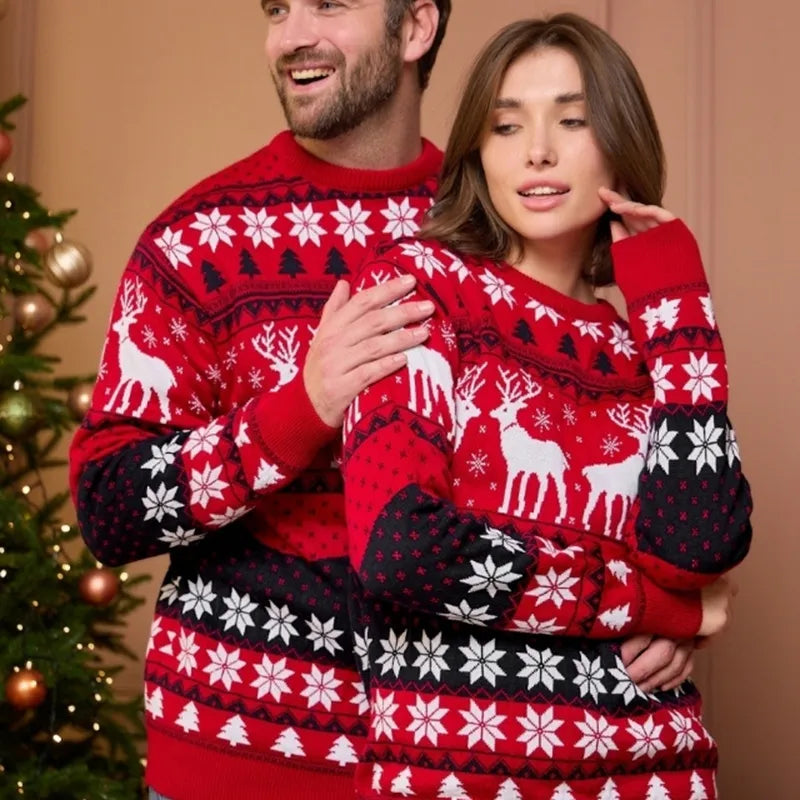 Couple portant des pulls de Noël rouges avec motifs de rennes et flocons de neige, près d'un sapin décoré. Mode festive, vêtements d'hiver.