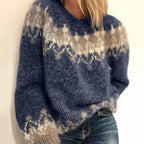 Pull en laine bleu avec motifs géométriques blancs et beiges, manches longues, porté par une femme. Mode hiver, style décontracté et tendance.