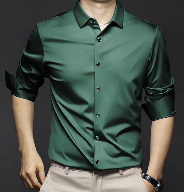 Homme portant une chemise verte satinée à manches longues retroussées, sur fond noir. Mode masculine élégante, tenue chic et moderne.