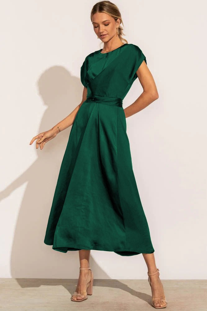 Robe verte élégante en satin, longueur mi-mollet, manches courtes, ceinture à la taille, portée par une femme, style chic et moderne.