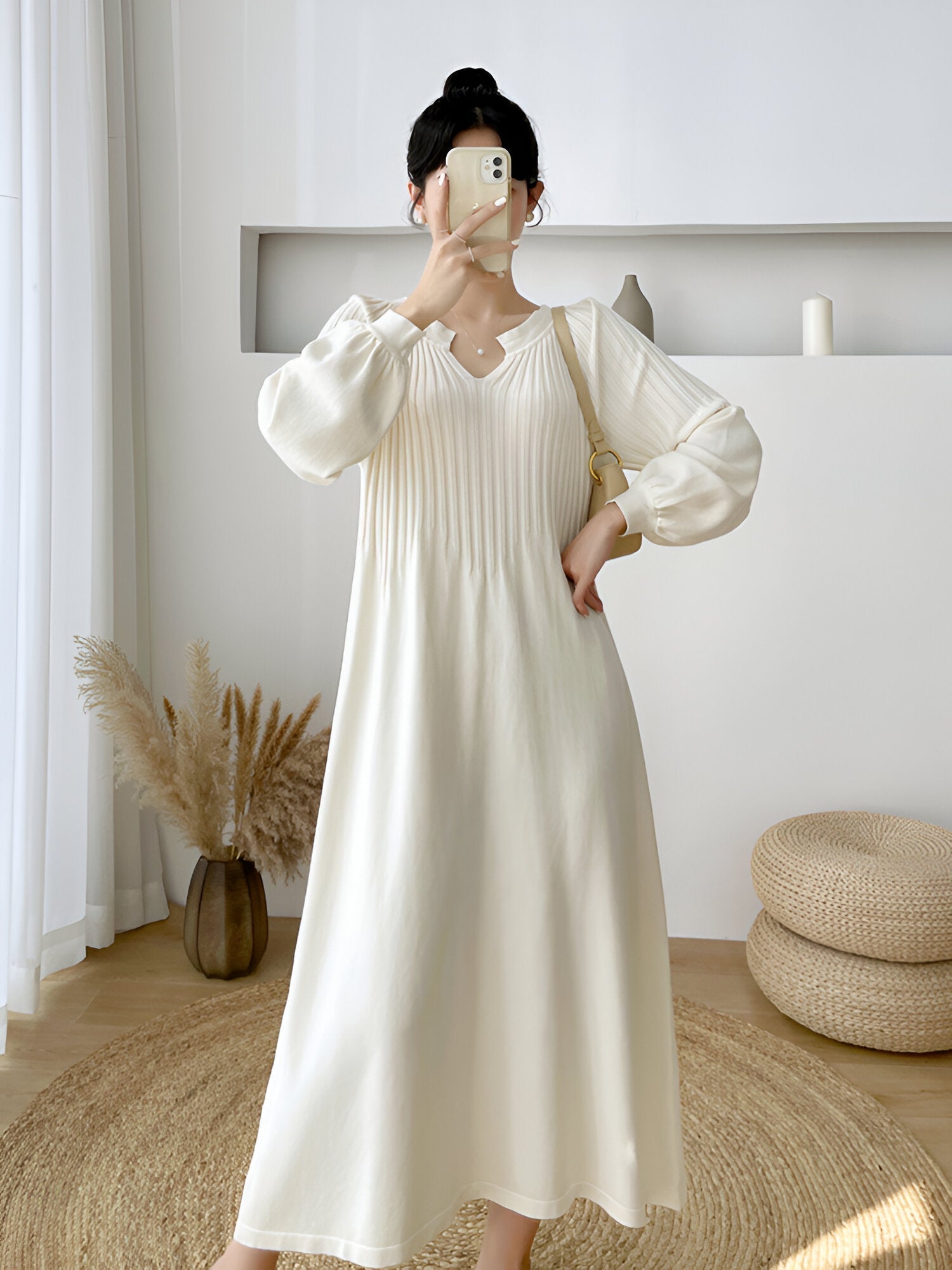 Robe longue blanche élégante avec manches bouffantes, femme prenant un selfie dans un intérieur moderne et minimaliste, décoration naturelle et épurée.