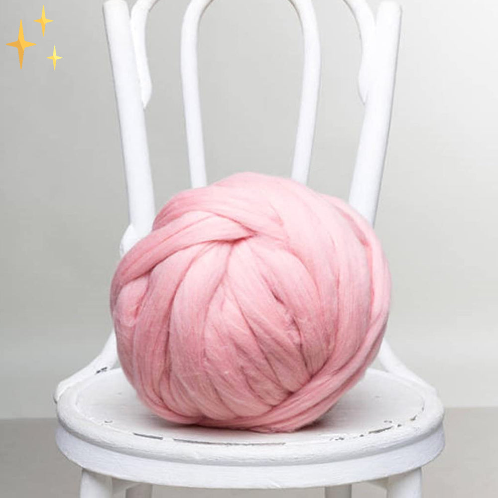 Grosse pelote de laine rose posée sur une chaise blanche, idéale pour le tricot XXL et la décoration intérieure moderne.