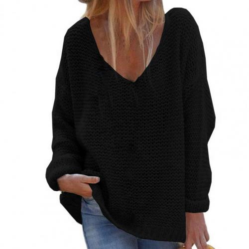 Femme portant un pull noir ample à col en V, manches longues, avec un jean bleu. Mode décontractée, tendance automne-hiver.