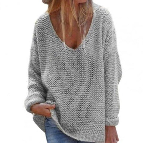 Femme portant un pull en maille gris ample, col en V, manches longues, style décontracté, mode automne-hiver, tendance féminine.