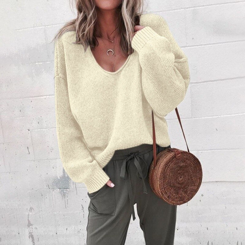 Femme portant un pull beige ample, pantalon vert olive, et sac rond en osier. Mode décontractée, tendance automne, style chic et confortable.