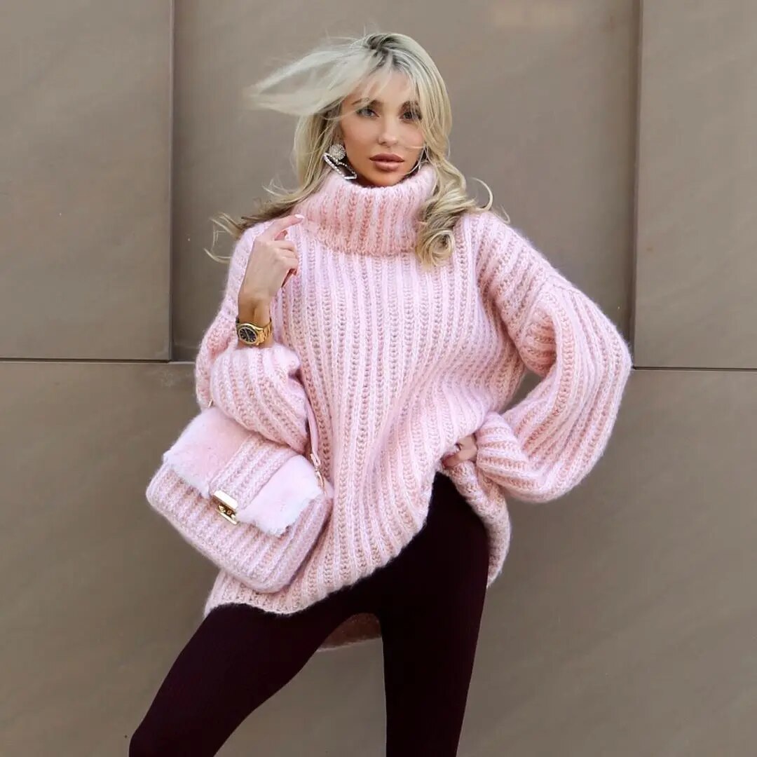Femme portant un pull rose en maille épaisse, posant avec un sac assorti. Mode automne-hiver, style élégant et tendance.