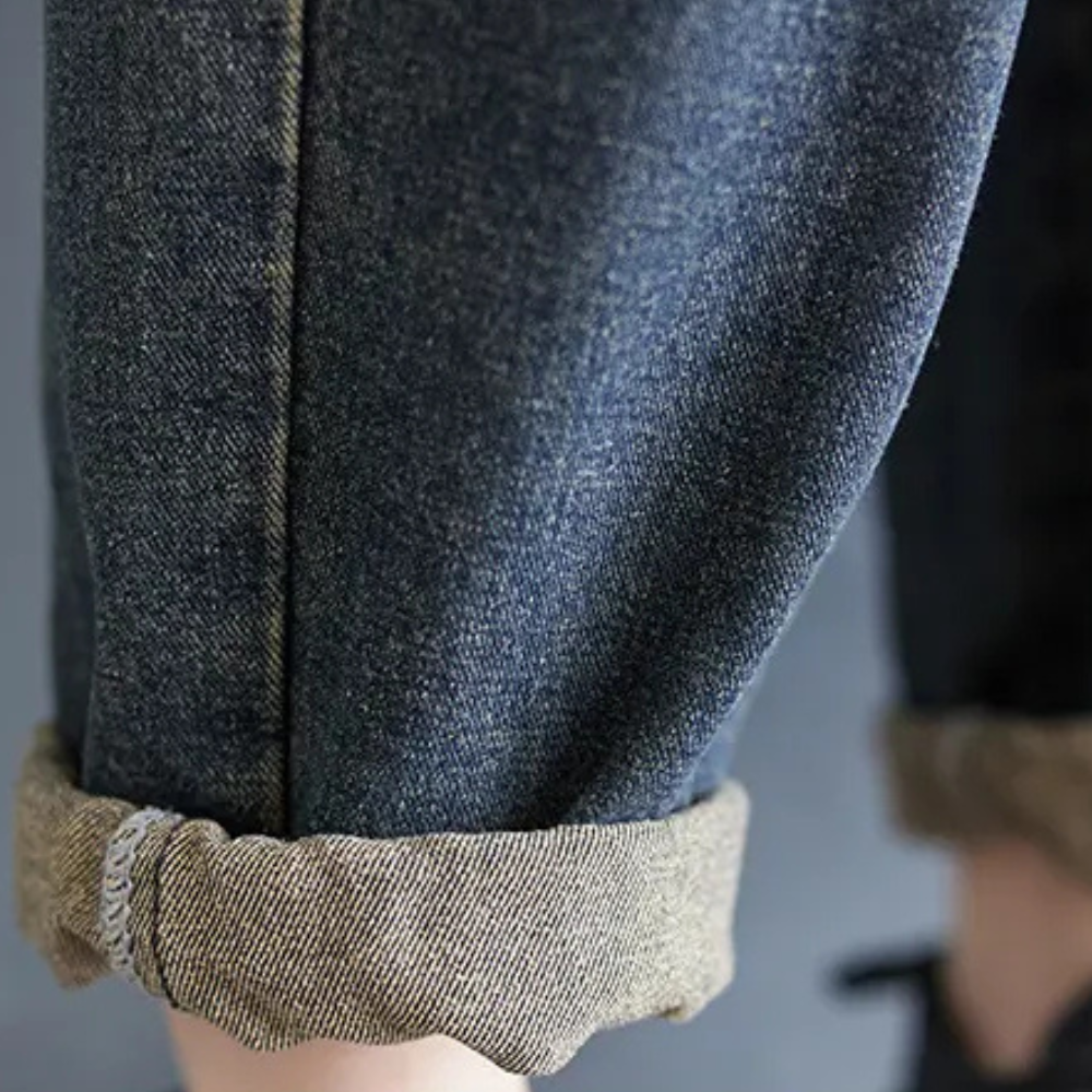 Jeans en denim bleu foncé avec ourlet retroussé, style décontracté, mode tendance, gros plan sur la texture du tissu, pantalon moderne.