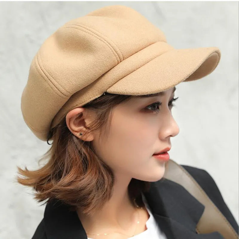 Femme portant une casquette gavroche beige en laine, style automne-hiver, mode féminine élégante, profil gauche, cheveux courts châtains.
