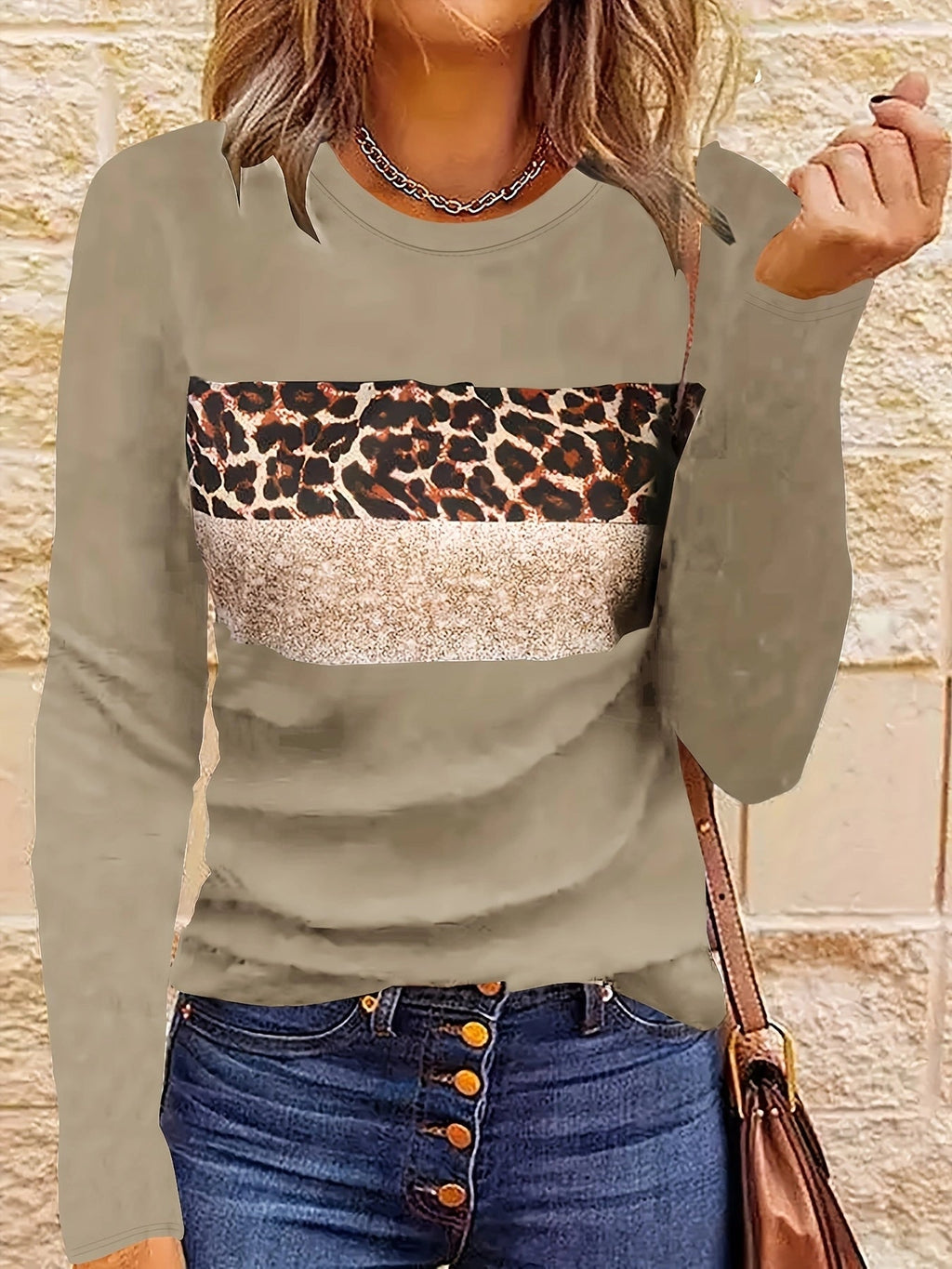 Femme portant un pull beige à motif léopard et paillettes, associé à un jean bleu à boutons. Mode automne chic et tendance.