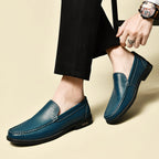 Chaussures mocassins en cuir bleu pour homme, élégantes et modernes, portées avec un pantalon noir. Accessoire mode masculin tendance.