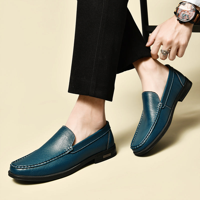 Chaussures mocassins en cuir bleu pour homme, élégantes et modernes, portées avec un pantalon noir. Accessoire mode masculin tendance.