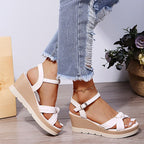 Sandales compensées blanches pour femme, avec lanières croisées, portées avec un jean déchiré. Chaussures d'été tendance et élégantes.